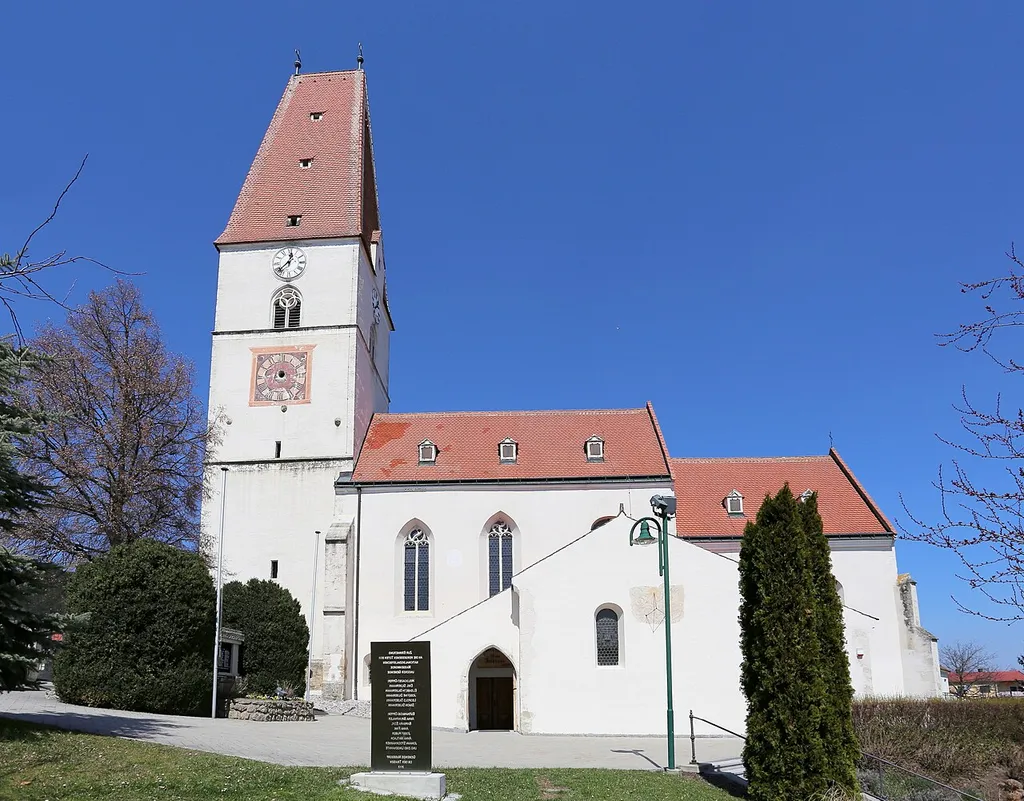 Katholische Pfarrkirche hl. Johannes der Täufer in der niederösterreichischen Marktgemeinde Nußdorf ob der Traisen. Ein zweischiffiger spätgotischer Sakralbau mit Westturm und einem klar abgesetzten Rechteckchor aus dem 14. Jahrhundert. Davor (in Spiegelschrift) das Mahnmal für die Opfer des Nationalsozialismus.
