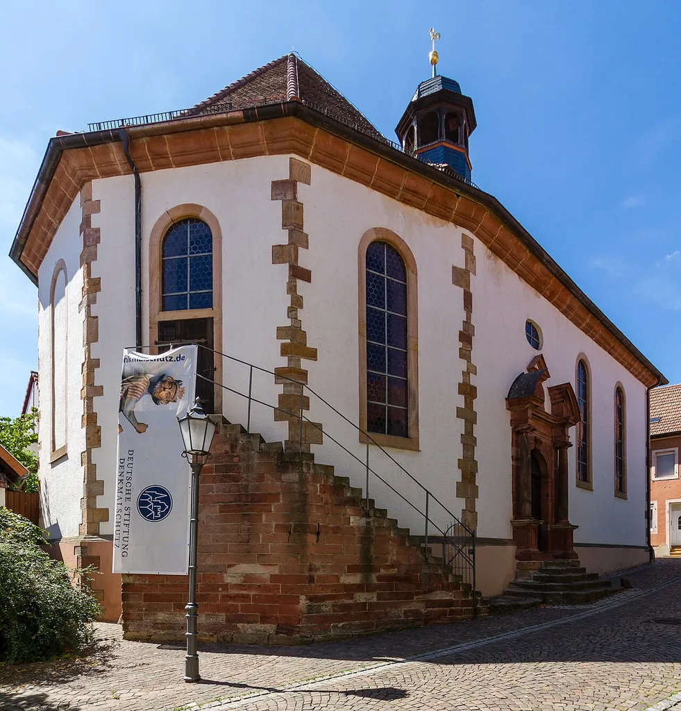 This is a photograph of a cultural monument.It is on the list of cultural monuments of Bad Bergzabern. Designation: Protestant mountain church Location: Obere Berggasse House number: 10 Place: Bad Bergzabern, Collective municipality Bad Bergzabern, District Südliche Weinstraße, Rhineland-Palatinate, Federal Republic of Germany Construction time: designated 1733 Description: Former Lutheran palace church, baroque hall building; bell, designated 1733