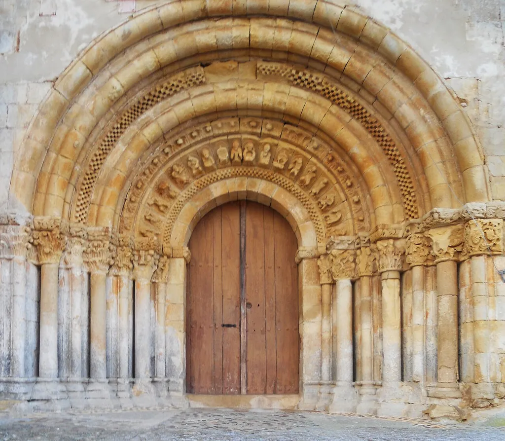 Main gate of church of San Pelayo in Arenillas de San Pelayo (Palencia, Castile and León). It is the splendid rest of whatever monastery "Dotado en 1132 por los familiares de Muño de Saldaña, que lo hicieron libre en 1159 y que pasó en 1168 a los premostratenses de Retuerta”. In spite of the successive remodelings has been suffering since the beginning of his career, this temple retains an elegant style still airy and proportionate distribution of their volumes. Contributes to this finding is exempt Southeast of the hamlet. Currently meets parish church and local cemetery, which is located at the header of the same functions. Spotlight your global doneness are the header and the portico. Seat, is composed of three apses, taller and proportion central and on the sides of minors, two added chapels comprising an elegant way to false cruise together. The header is plastered protecting the brick. The central apse is smooth, except for a central band that we have a profusion of intermingled decorative and functional elements: three elongated dept and blinded Windows - which in turn would bring light to the interior - are arranged at regular intervals. Between them and in succession 1-3 - 3-1, other smaller in height the same doneness, blind from source, complete the bottom of the decoration. On it, and at regular intervals, 10 vain blind rectangular and rehundidos, with the same style of apparently are arranged in succession 1-4 - 4-1, separated by the upper area of the elongated Windows and tresbolillados to the lower elements. Late era opened a large window square on the North by removing some of the vain described (two of the upper and one lower apart from the north side window) side. A succession of smooth canecillos underpin the cornice. This decorative style of the central apse is characteristic do the Valdavia area mudéjar, and certainly that under the stucco header will be another copy of the "brick Romanesque". The smaller apses focused by spilled window are loca