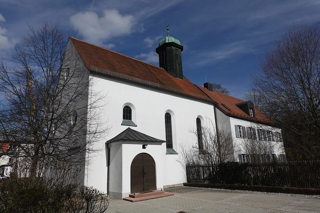 Verputzter barockisierender Saalbau mit Satteldach, Dachreiter und Eingangsportal; mit Ausstattung; nach Osten baulich angeschlossenes Pfarrhaus, zweigeschossiger Satteldachbau über hohem Sockelgeschoss; nach Entwürfen des Erdinger Stadtbaumeisters Hugo Schmid, 1930/31