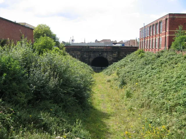 Deepdale No 3 Tunnel, Preston The Preston &amp; Longridge Railway was opened in 1840, the primary purpose for its promotion being to carry stone from Longridge Fell for use in public buildings in Preston and the docks at Liverpool. From its terminus on the banks of the Lancaster Canal at Maudlands it ran through a series of closely-spaced tunnels totalling half a mile in length under Deepdale. This is the easternmost portal of the tunnels, taken from St Pauls Road bridge. The line, which latterly served a coal yard at Deepdale, has been disused for a number of years but there is still a single line of rails beneath the grass. Just visible in the far background above the tunnel is the spire of St Walburge's Church, possibly the tallest church spire in Preston.
