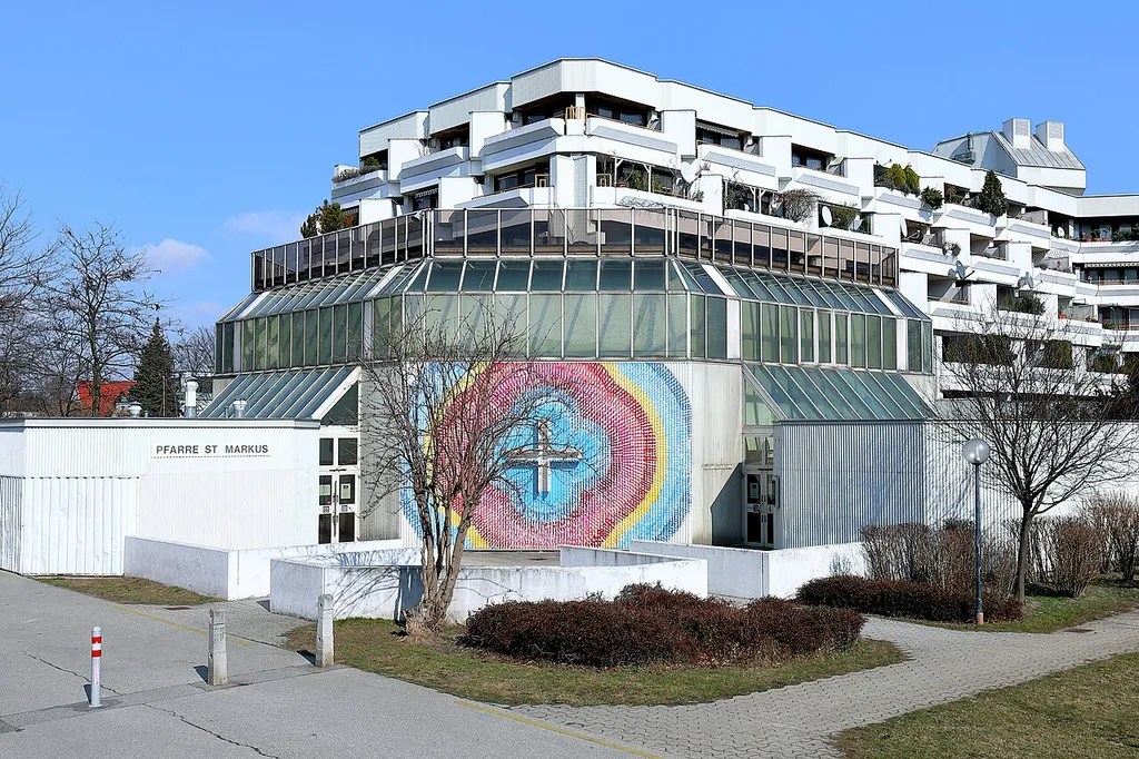 Südwestansicht der Pfarrkirche St. Markus in Großjedlersdorf, ein Bezirksteil des 21. Gemeindebezirks Floridsdorf der österreichischen Bundeshauptstadt Wien.Die Kirche wurde als Teil des Gemeindebaues „Heinz-Nittel-Hof“ errichtet und im Mai 1983 geweiht. Die Planung des Gemeindebaues mit rd. 1400 Wohneinheiten und der Kirche hatte das Architekturbüro Harry Glück &amp; Partner inne.