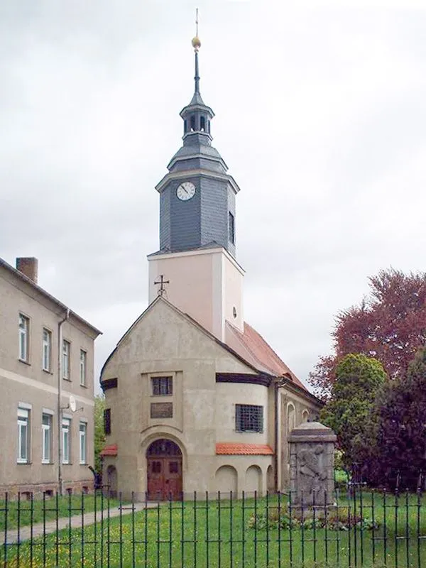 Frontansicht der Katharinenkirche zu Großdeuben, davor das Denkmal der Gefallenen der beiden Weltkriege und die alte Schule
