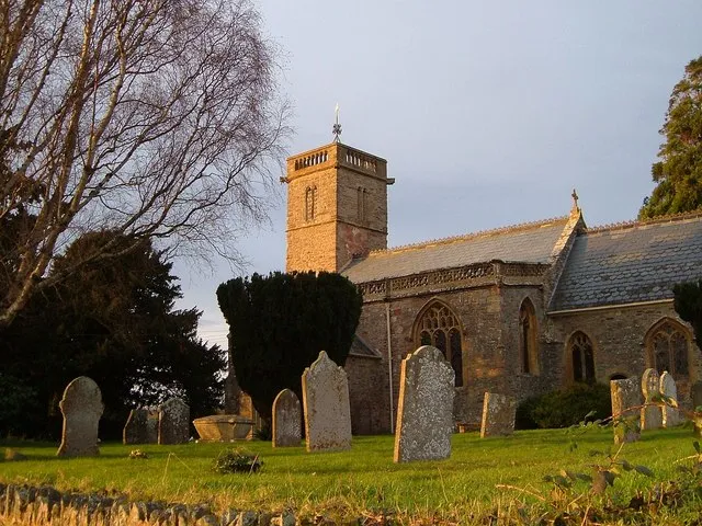 St Mary's church, Cheddon Fitzpaine Built of "red sandstone and blue lias random rubble, Ham stone dressings", and with a late C13 tower which has a C19 parapet added, the church and its churchyard are raised above the village street.