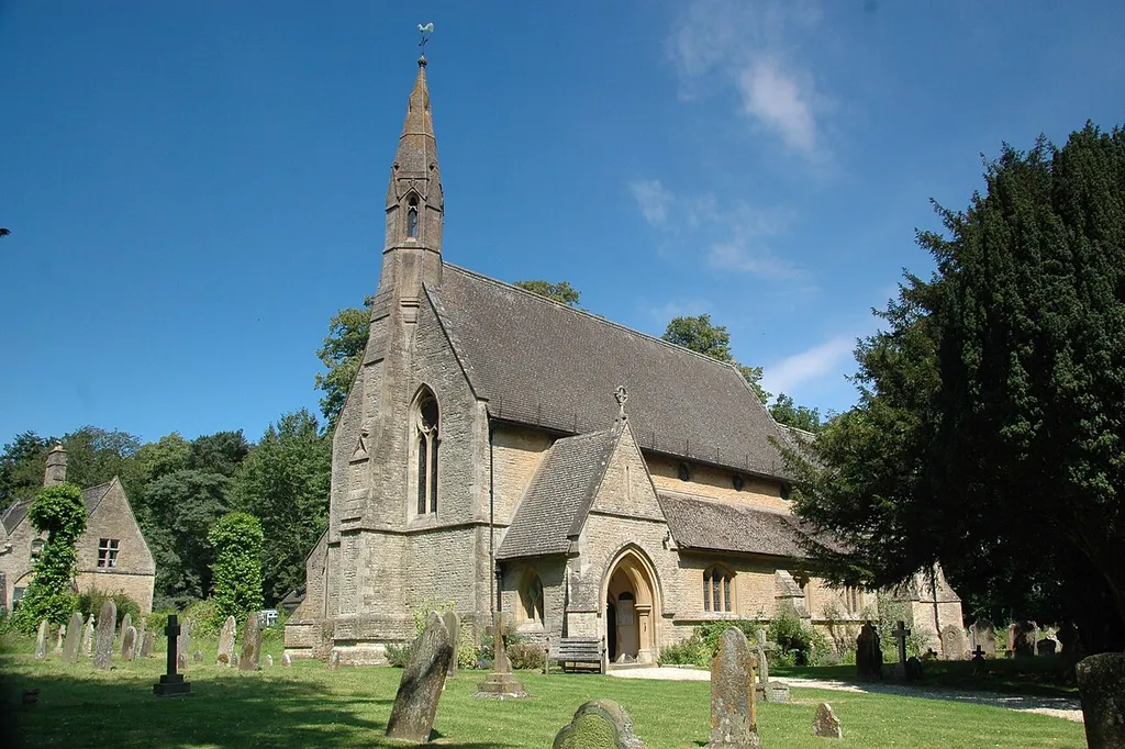 Church of England parish church of Saints Simon and Jude, Milton-under-Wychwood, Oxfordshire: view from the southwest. On the left beyond the churchyard is part of the former parish school, which is now a private house.