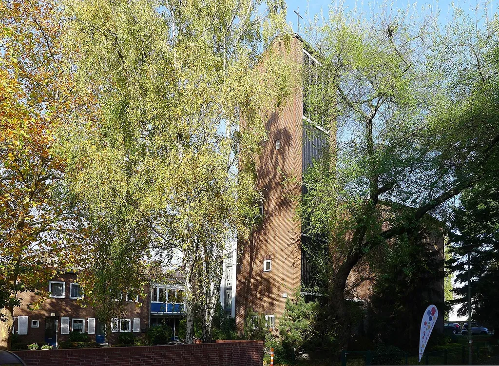 Hinter Bäumen versteckt befindet sich die Kirche, sodass sie vom Brunsbütteler Damm nicht zu sehen ist.