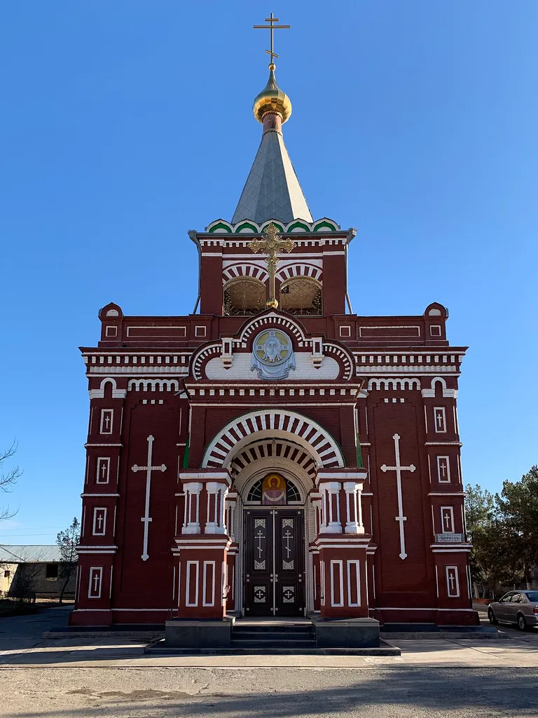 The picture shows the red façade of the building, with different symbols of Christian iconography, such as the Holy Face of Jesus. The church was built in the year 1900.