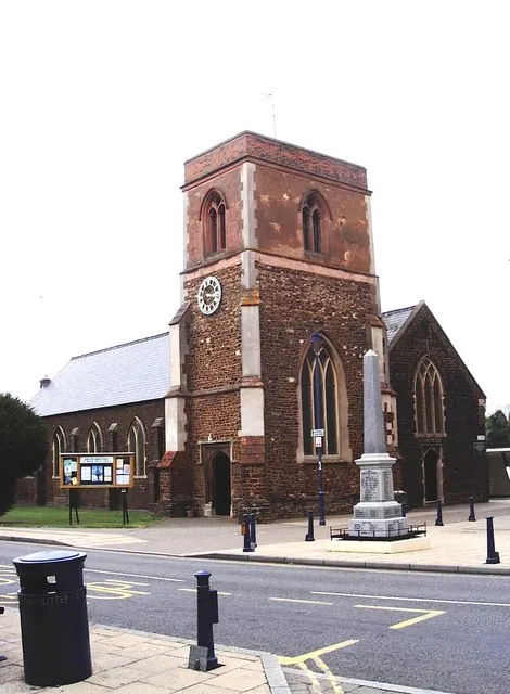 Parish church of St Michael and All Angels, Shefford, Bedfordshire, seen from west-northwest from the High Street. The church is built mainly of carstone, an iron-bearing sandstone in the Woburn sand formation of the local lower greensand. The pale stones in the tower are blocks of local hard chalk.
