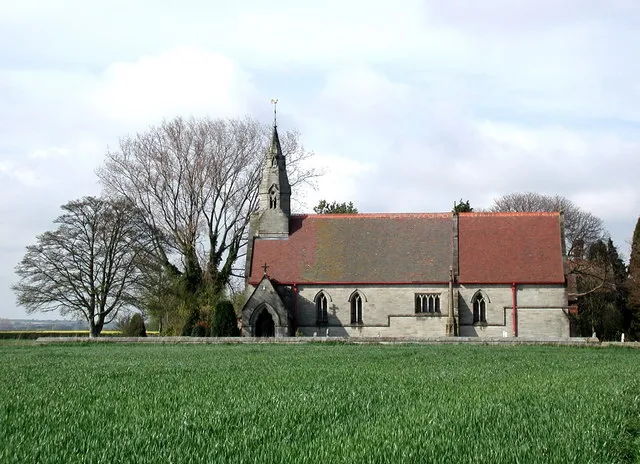 View north across a field beside Nafferton Road, Wansford, East Riding of Yorkshire, England, to the parish church of St Mary the Virgin. The church was built in 1868 along with the vicarage, school and schoolhouse, for the Sykes family of Sledmere.