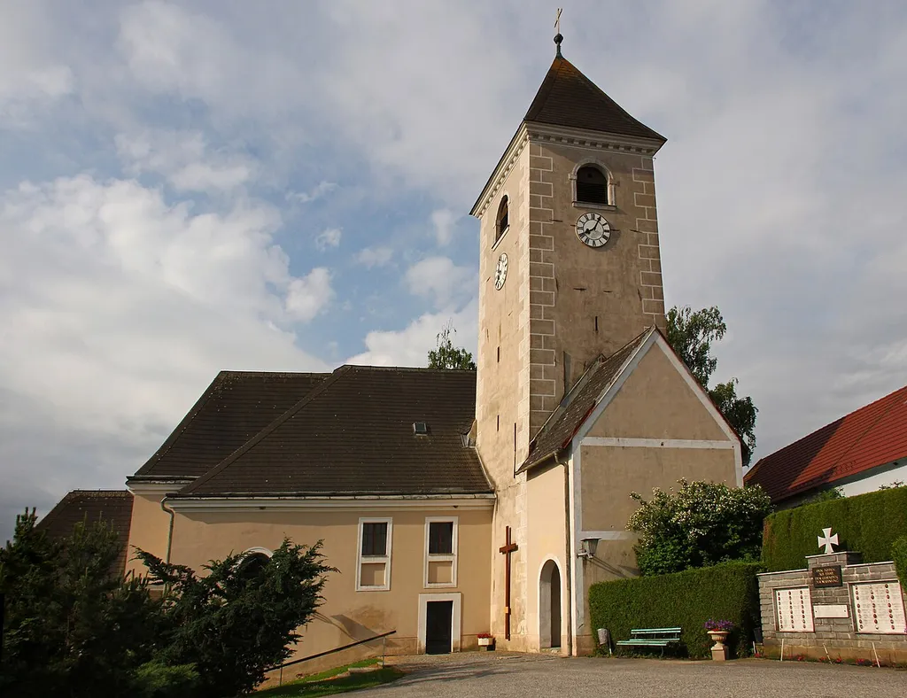 Die Pfarrkirche St. Anna, erhöht im Westen über dem Ort am Anstieg einer Geländestufe gelegen, ist von der Mauer des ehemaligen Friedhofs umgeben.