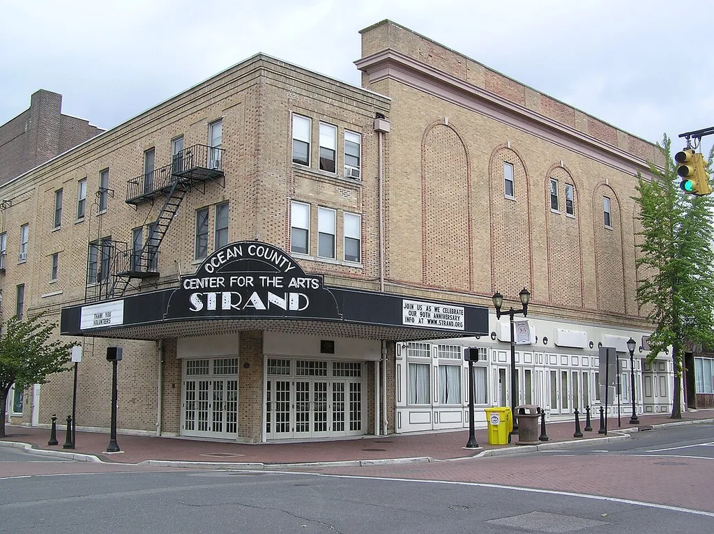 Strand Theater, 400 Clifton Avenue, Lakewood, NJ. The upper two floors of the building above the marquee and to the left of the photo are apartments. The raised area of the building to the left top of the photo is the stage area. The projection booth for movies was located at the windows to the right. The building is currently occupied by the Ocean County Center for the Arts.