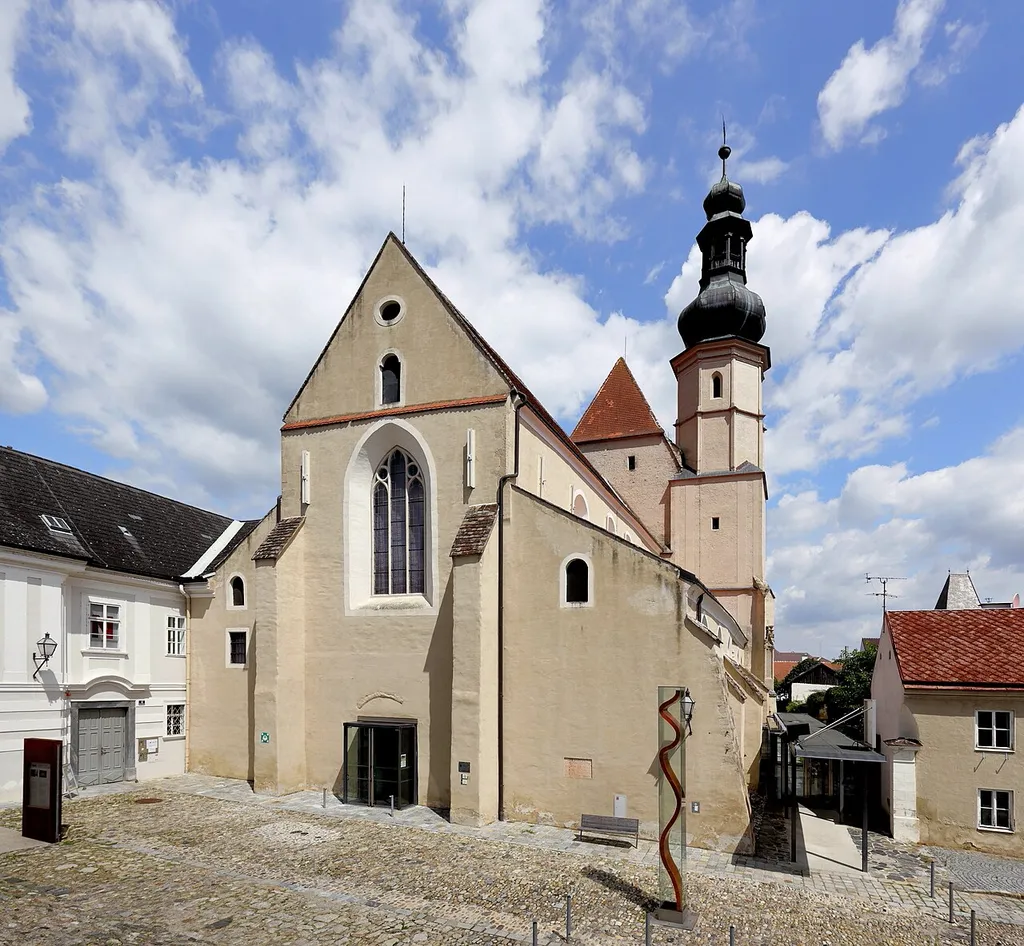 Südwestansicht der ehemaligen Minoritenkirche in Stein an der Donau, ein Stadtteil der niederösterreichischen Stadt Krems.Nachdem um 1223/24 die Minoriten in Stein ein Kloster gründeten, erfolgte 1264 die Kirchenweihe. Die spätromanische bzw. frühgotische dreischiffige Basilika hat einen höheren, einschiffigen gotischen Langchor, der vermutlich um 1330 gebaut wurde, und einen Südturm mit barocker Bekrönung, der um 1444 errichtet wurde. Zur Reformationszeit wurde der Kirchenbau bis 1577 als Salzdepot genutzt und 1592 erfolgte die Rückgabe an die Minoriten. Mit der Aufhebung des Klosters im Jahre 1790/96 wurde auch die Kirche profaniert und anschließend unter anderem als Tabakmagazin und Feuerwehrdepot verwendet. 1950/51 wurde die Kirche saniert und ab 1992 von der Kunsthalle Krems genutzt. Im Jahr 2002 erfolgte die Übernahme des Kirchenraumes durch die NÖ Festival und Kino GmbH und es fand anschließend bis 2004 eine neuerliche umfassende Renovierung durch den Architekten Fritz Göbl statt. Unter anderem wurde dabei auch südseitig ein neuer Zugangsfoyer errichtet. Die Kirche wird nun als „Klangraum Krems“ vermarktet.