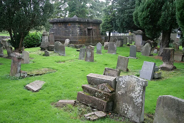 The Old Kirkyard, Dalmellington There are some very old stones in the graveyard. The MacAdam Cathcart of Craigengillan mausoleum is in the background.