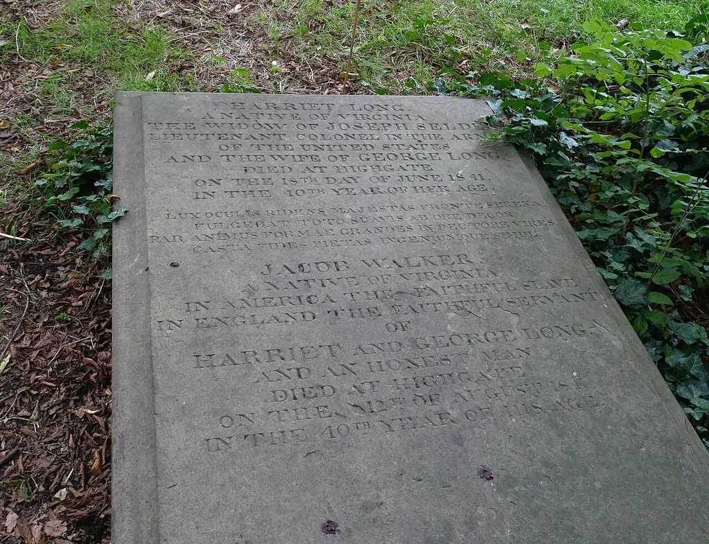 The Grade II listed resting place of Harriet Long, the wife of classical scholar George Long and their slave Jacob Walker, located along the southern perimeter of the churchyard around Saint Mary's Tower, Hornsey. Walker was listed as a man servant in the 1841 census upon the couple' return to England. This is a photo of listed building number 1392351.