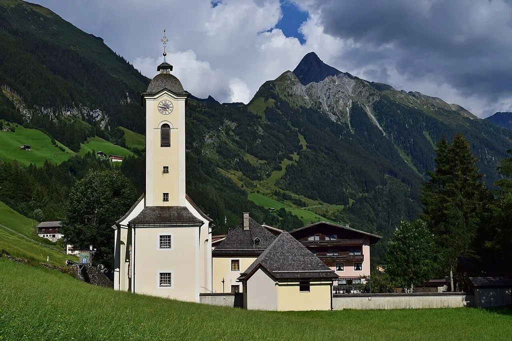 Kath. Pfarrkirche Hl. Kreuz in Brandberg und Friedhofskapelle mit Friedhof. Im Hintergrund der Berggipfel Brandberger Kolm.