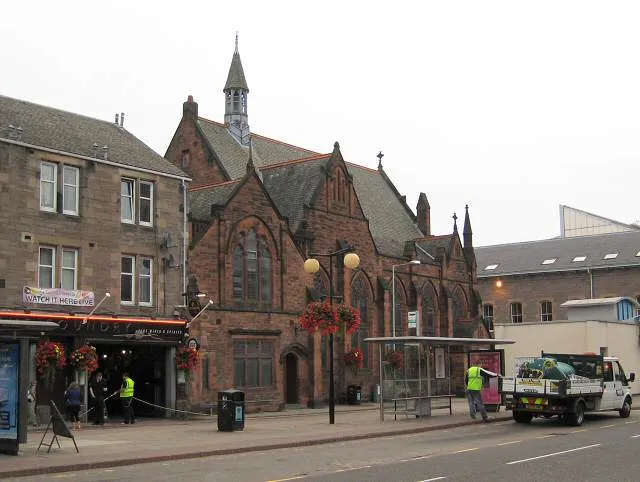 Mill Street, Perth The Congregational church stands at the corner of Mill Street and Kinnoull Street next to one pub and opposite another. On the opposite side of Kinnoull Street you can see part of the recently-built council offices. The vehicle parked next to the bus stance by the church is providing water for the hanging baskets.