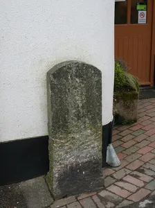 Milestone, opp. church entrance, beside shop wall, opp Burrington Post Office