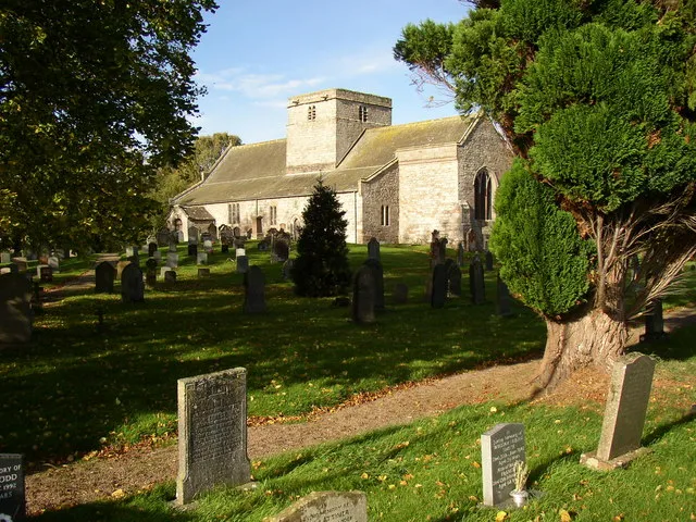 St Michael's Church, Barton, near to Tirril, Cumbria, Great Britain. The low central tower is Norman (c.1150) with walls 1.5m thick. The west and east tower arches are original, but were strengthened c.1300; there is a high tunnel-vault through the tower. There is also a Norman doorway in the north aisle. The chancel east window of three stepped lancets is 13C, and most of the other windows are of the Late Perpendicular period. The south aisle was built c.1250 and the north aisle c.1300. The roof-slates are fixed with sheep's shank bones instead of nails. The south porch is 17C, with a shield quartered with the arms of the Lowther, Lancaster, Beauchamp and Hartson families. On the north side is a mounting block close to where there was stabling for six horses. The church was restored in 1904.