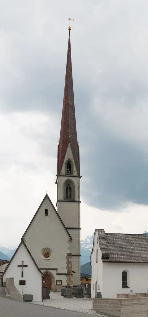 Die Kath. Pfarrkirche hl. Stephanus mit dem Kriegerdenkmal (links) und der Friedhofskapelle in Karres, Tirol, Österreich.
