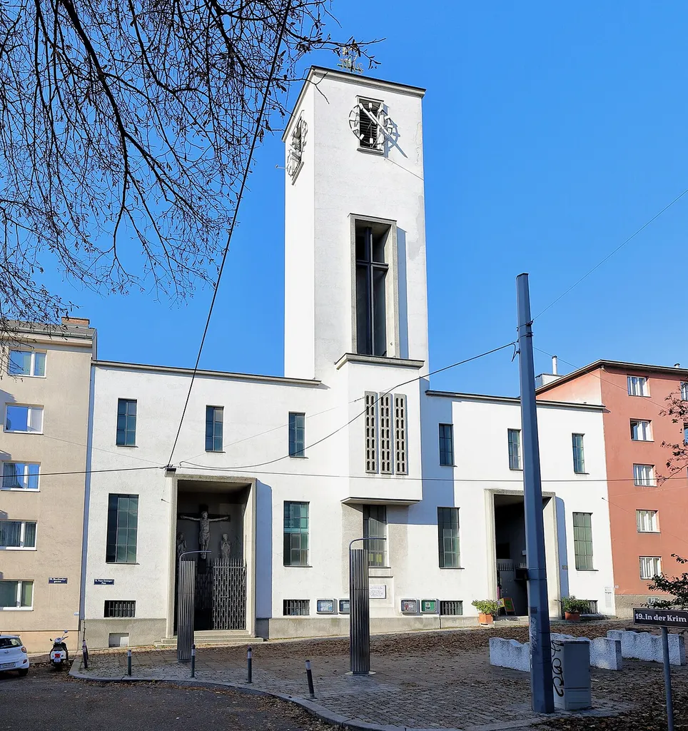 Südostansicht der röm.-kath. Pfarrkirche hl. Judas Thaddäus, auch Krimkirche bezeichnet, im 19. Wiener Bezirk Döbling.Die Kirche wurde von 1931 bis 1932 nach Plänen des Architekten Clemens Holzmeister errichtet. In den Jahren 1955 bis 1957 wurde die Kirche westseitg nach den Plänen des Architekten Anton Steflicek um das heutige Hauptschiff und Chor erweitert. Das ursprüngliche Kirchengebäude mit den Kirchturm wurde dadurch zum Querschiff mit einem Nebenaltar bzw. Seitenkapelle.