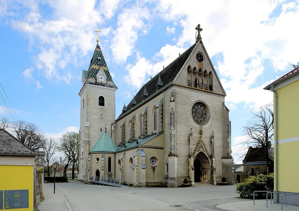 Westnordwestansicht der katholischen Pfarrkirche Mariae Himmelfahrt in der niederösterreichischen Marktgemeinde Großengersdorf. Der Chor mit 5/8-Schluß wurde Ende des 14. Jahrhunderts errichtet und das Untergeschoß des wuchtigen Nordturmes stammt aus dem 15. Jahrhundert. Das neogotische Langhaus wurde von 1897 bis 1901 nach Plänen des Architekten Eugen Schweigl errichtet.