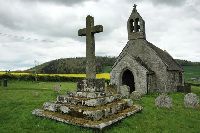 St Davids' parish church, Trostrey, Monmouthshire, seen from the west. The churchyard cross in the foreground has a Mediæval base and steps with a modern shaft and head.